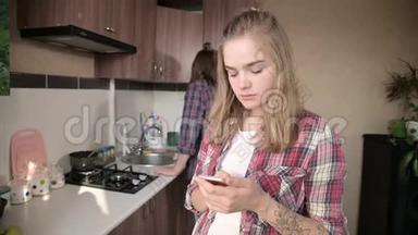 年轻的夫妻在厨房里。 一个有纹身的女孩在手机上<strong>给</strong>她的<strong>爱人</strong>写了一条信息